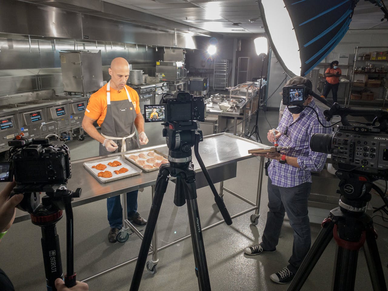 Chef filmed in a professional kitchen setup for a cooking show with full camera crew.